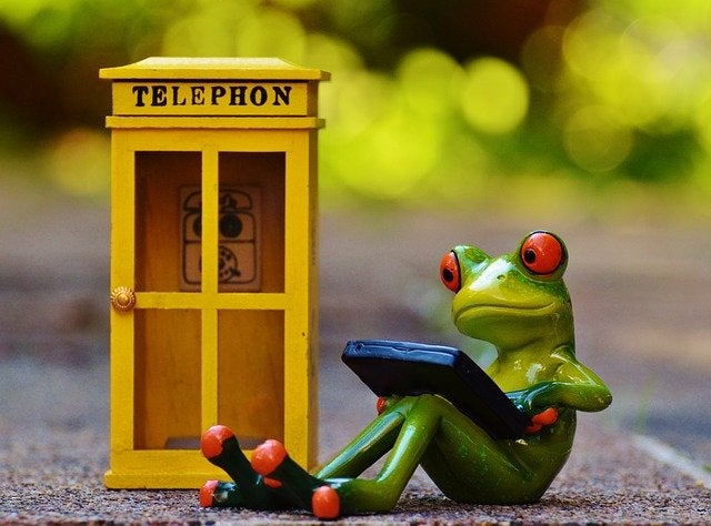 frog using cellphone outside of a yellow phonebooth
